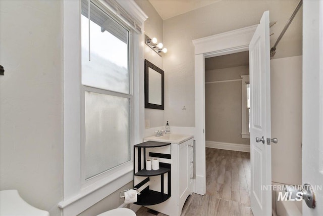 bathroom with vanity, toilet, wood finished floors, and baseboards