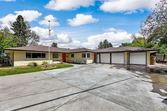 single story home with brick siding, a front yard, concrete driveway, and an attached garage