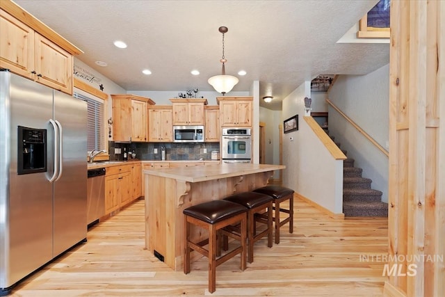 23 Waterline Ln, Cascade, ID 83611 - kitchen featuring stainless steel appliances, light brown cabinetry, light wood finished floors, backsplash, and light countertops