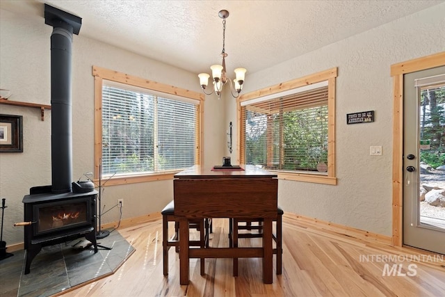23 Waterline Ln, Cascade, ID 83611 - dining space featuring a wood stove, a textured wall, light wood finished floors, a chandelier, and a textured ceiling