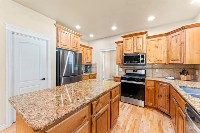 kitchen featuring stainless steel appliances, light wood-type flooring, backsplash, and a center island