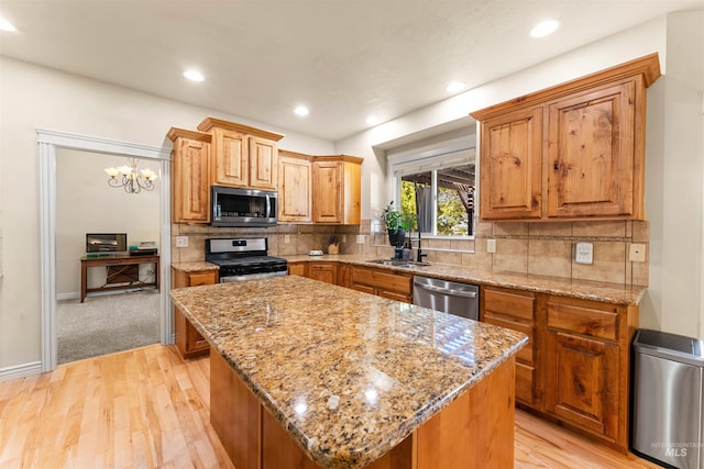 kitchen with stainless steel appliances, tasteful backsplash, a sink, and light stone countertops