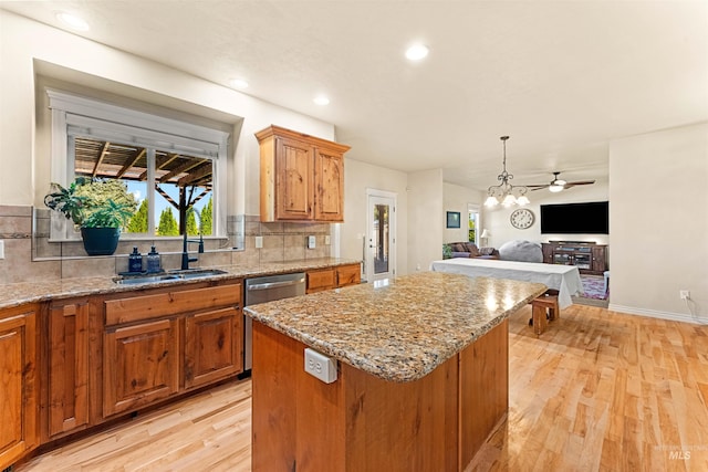 kitchen featuring light stone counters, a center island, light wood-style floors, brown cabinetry, and open floor plan