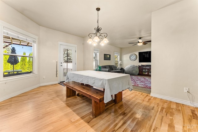 dining space featuring light wood-style floors, baseboards, and ceiling fan with notable chandelier