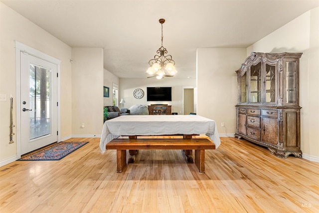 dining space with light wood-type flooring, an inviting chandelier, and baseboards