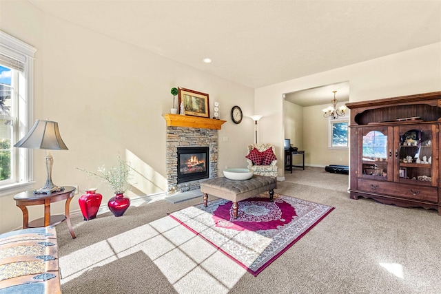 carpeted living room with a stone fireplace, an inviting chandelier, and baseboards