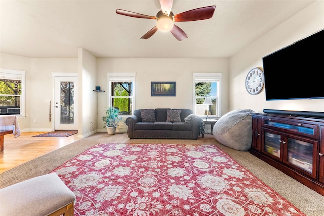 living room featuring light colored carpet, ceiling fan, and baseboards