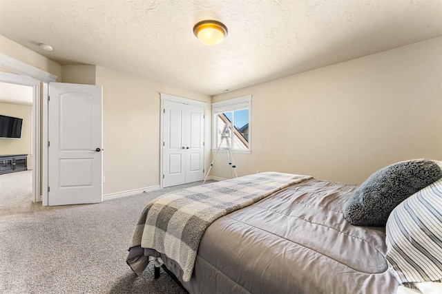 carpeted bedroom featuring a closet, a textured ceiling, and baseboards