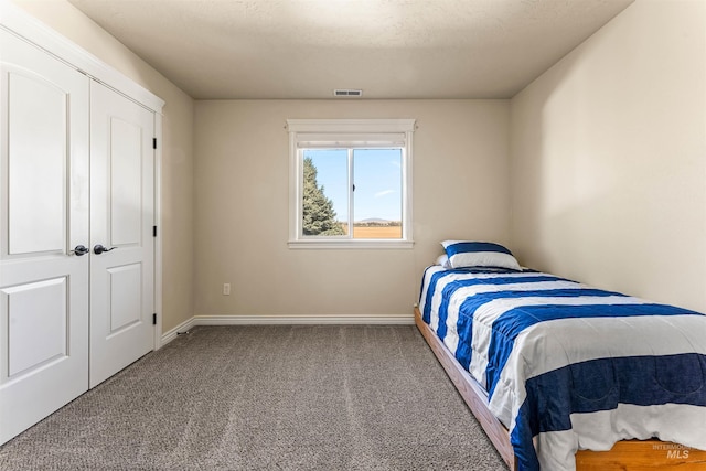 carpeted bedroom featuring baseboards, visible vents, and a textured ceiling