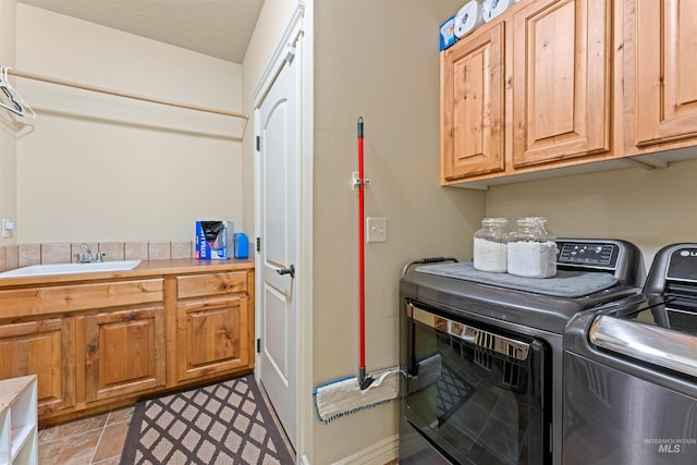 clothes washing area with cabinet space, a sink, and washing machine and clothes dryer