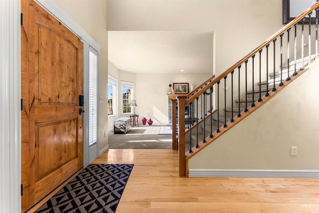 entryway with baseboards, stairway, and wood finished floors