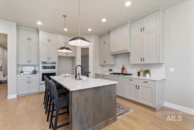 11966 W Zamalek Ct, Kuna, ID 83634 - kitchen with appliances with stainless steel finishes, light wood-style floors, light countertops, a kitchen island with sink, and recessed lighting