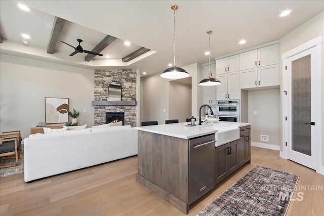 11966 W Zamalek Ct, Kuna, ID 83634 - kitchen with stainless steel appliances, ceiling fan, light countertops, light wood finished floors, and white cabinetry