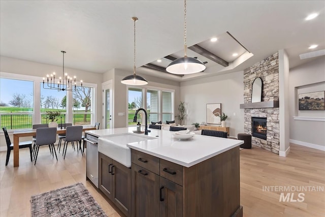 11966 W Zamalek Ct, Kuna, ID 83634 - kitchen with dark brown cabinetry, dishwasher, light countertops, light wood-style flooring, and a stone fireplace