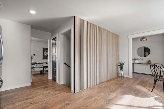 corridor with wood finished floors, an upstairs landing, baseboards, and recessed lighting