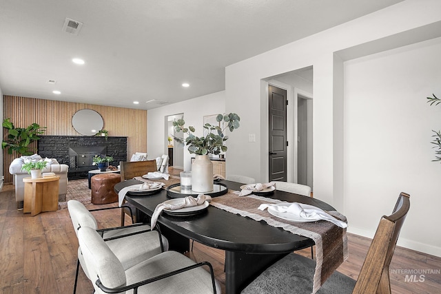 dining room with an accent wall, wood finished floors, recessed lighting, and baseboards