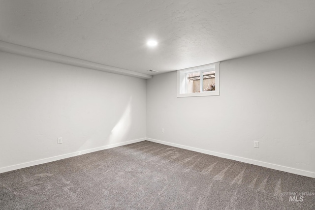 below grade area with dark carpet and baseboards