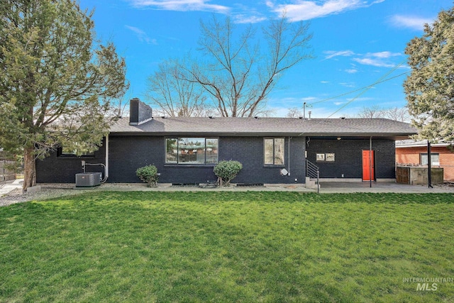 rear view of property featuring central air condition unit, a patio area, a chimney, brick siding, and roof with shingles