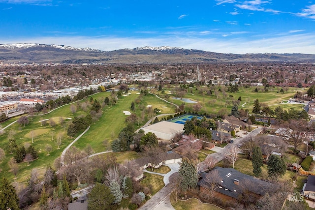 view of property location featuring a local golf course, a mountain backdrop, and nearby suburban area