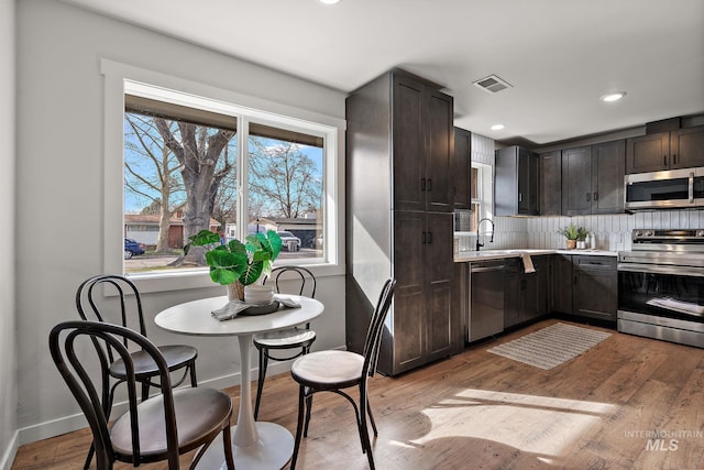 kitchen featuring stainless steel appliances, dark brown cabinets, backsplash, light countertops, and recessed lighting