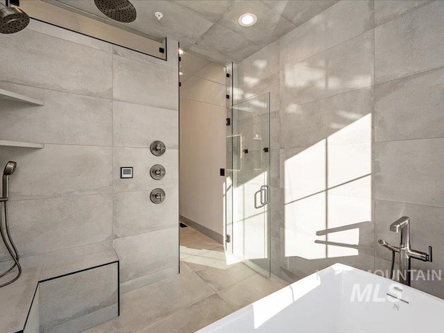 full bathroom with tile walls, a soaking tub, and a shower stall