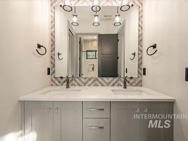 full bathroom featuring double vanity, visible vents, backsplash, and a sink