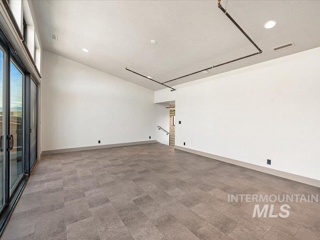 spare room featuring baseboards, visible vents, recessed lighting, and a textured ceiling