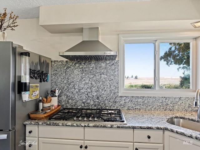 kitchen with sink, appliances with stainless steel finishes, white cabinetry, island range hood, and decorative backsplash