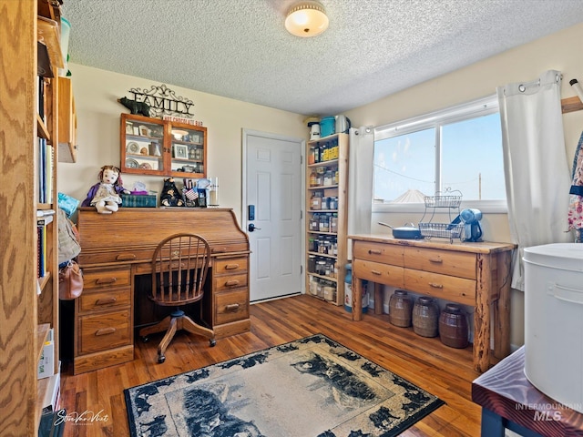 home office with hardwood / wood-style floors and a textured ceiling