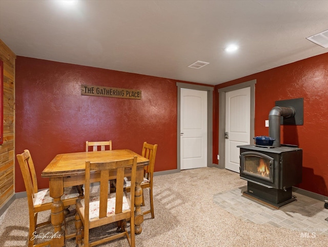 dining room featuring a wood stove and light colored carpet