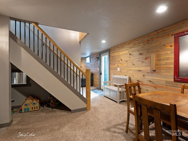 carpeted dining area featuring wooden walls