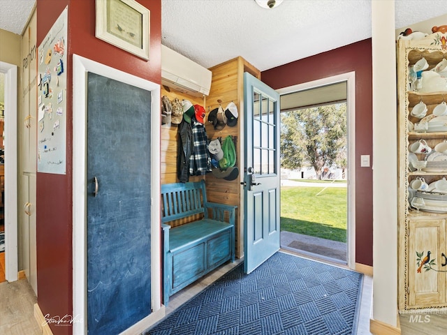 interior space featuring wood-type flooring, a wall mounted AC, and a textured ceiling