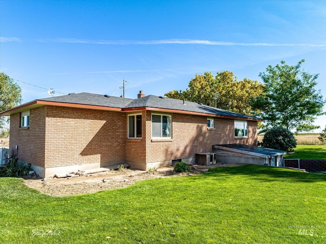 rear view of house featuring cooling unit and a lawn