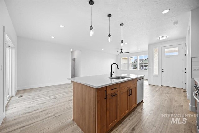 kitchen featuring a sink, light wood-style flooring, brown cabinetry, stainless steel dishwasher, and recessed lighting