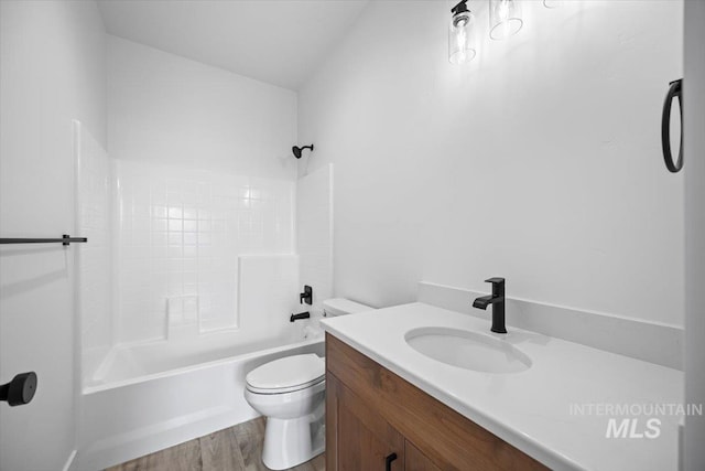 bathroom with toilet, wood finished floors, vanity, and tub / shower combination
