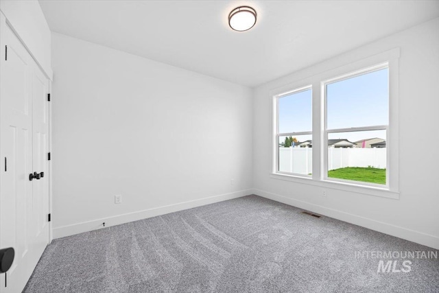 spare room featuring carpet and baseboards