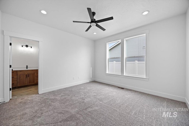 unfurnished bedroom featuring carpet floors, baseboards, recessed lighting, ensuite bathroom, and ceiling fan