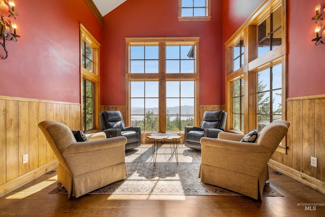 living room with high vaulted ceiling, wood walls, and hardwood / wood-style flooring