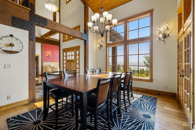 dining room featuring a notable chandelier, light hardwood / wood-style flooring, french doors, and high vaulted ceiling