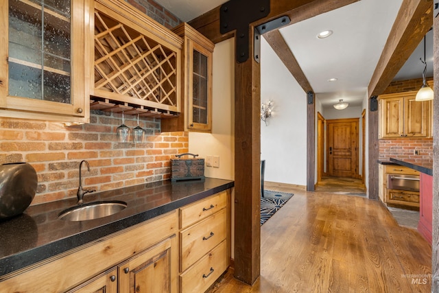 kitchen with dark stone counters, decorative light fixtures, sink, and light wood-type flooring