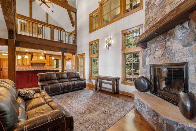 living room with a fireplace, ceiling fan, hardwood / wood-style flooring, sink, and high vaulted ceiling