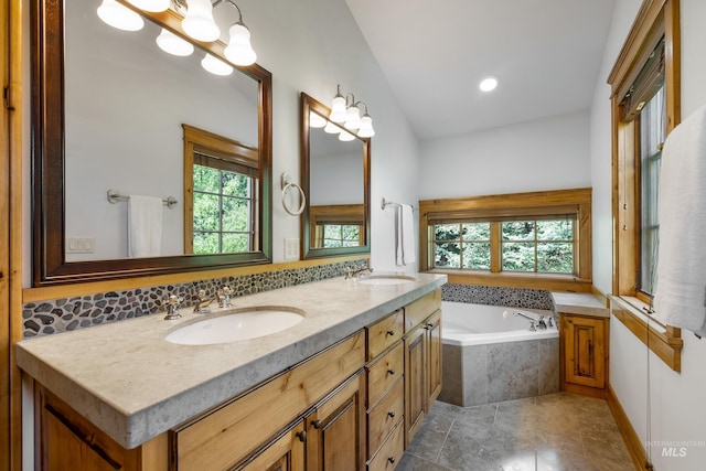 bathroom with tiled tub, tile patterned flooring, a healthy amount of sunlight, and dual bowl vanity