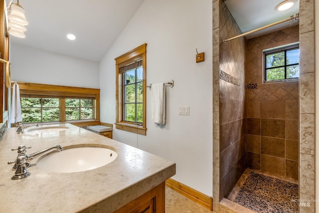 bathroom with tiled shower, lofted ceiling, and vanity