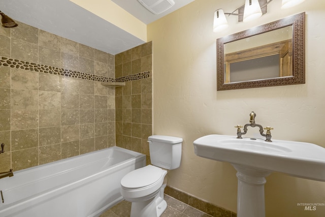 bathroom with tile patterned floors, toilet, and tiled shower / bath