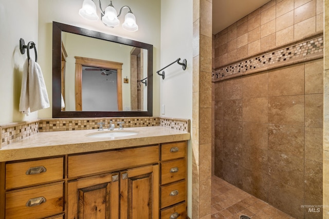 bathroom with tiled shower, vanity, and backsplash