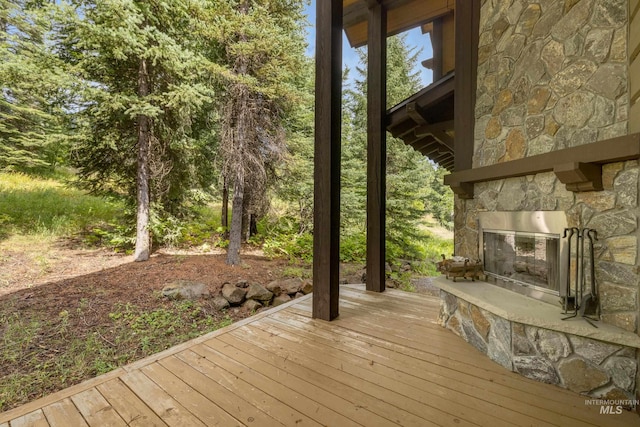 wooden deck featuring an outdoor stone fireplace