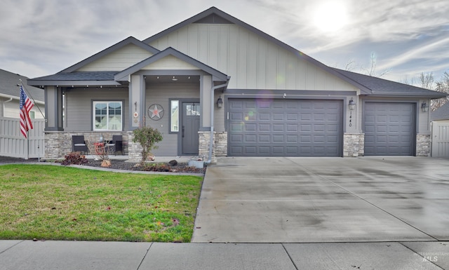 craftsman house featuring a front lawn, stone siding, board and batten siding, and a garage