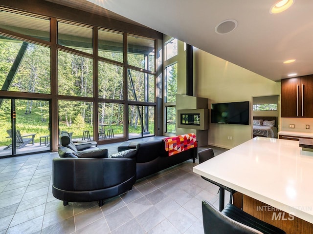 1115 Heavens Gate Ct, Mccall, ID 83638 - living room featuring light tile patterned flooring, high vaulted ceiling, a wall of windows, and baseboards