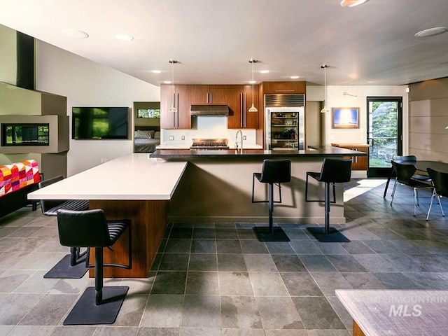 1115 Heavens Gate Ct, Mccall, ID 83638 - kitchen with built in refrigerator, under cabinet range hood, a breakfast bar, recessed lighting, and a large island