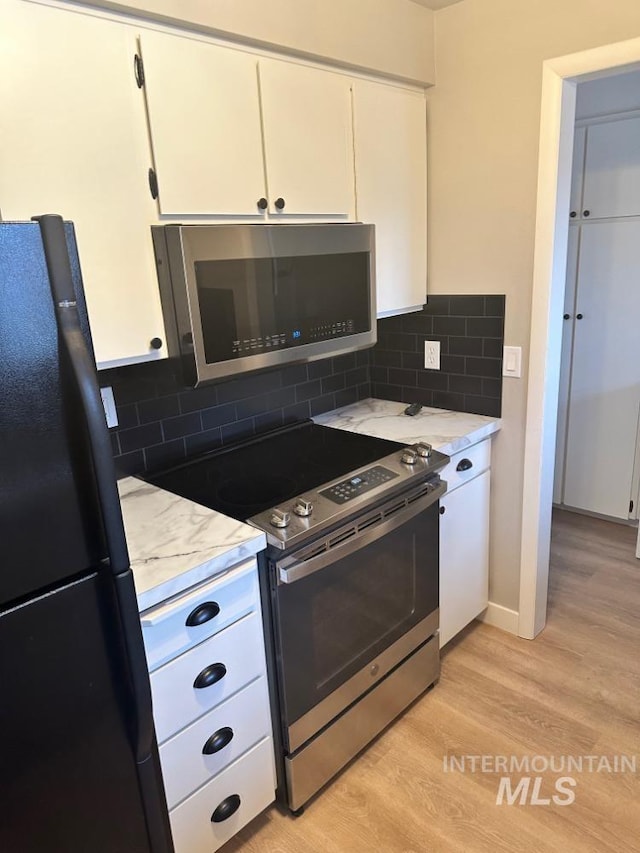3109 N Tamarack Dr, Boise, ID 83703 - kitchen with white cabinetry, light stone countertops, light wood-style flooring, decorative backsplash, and stainless steel appliances